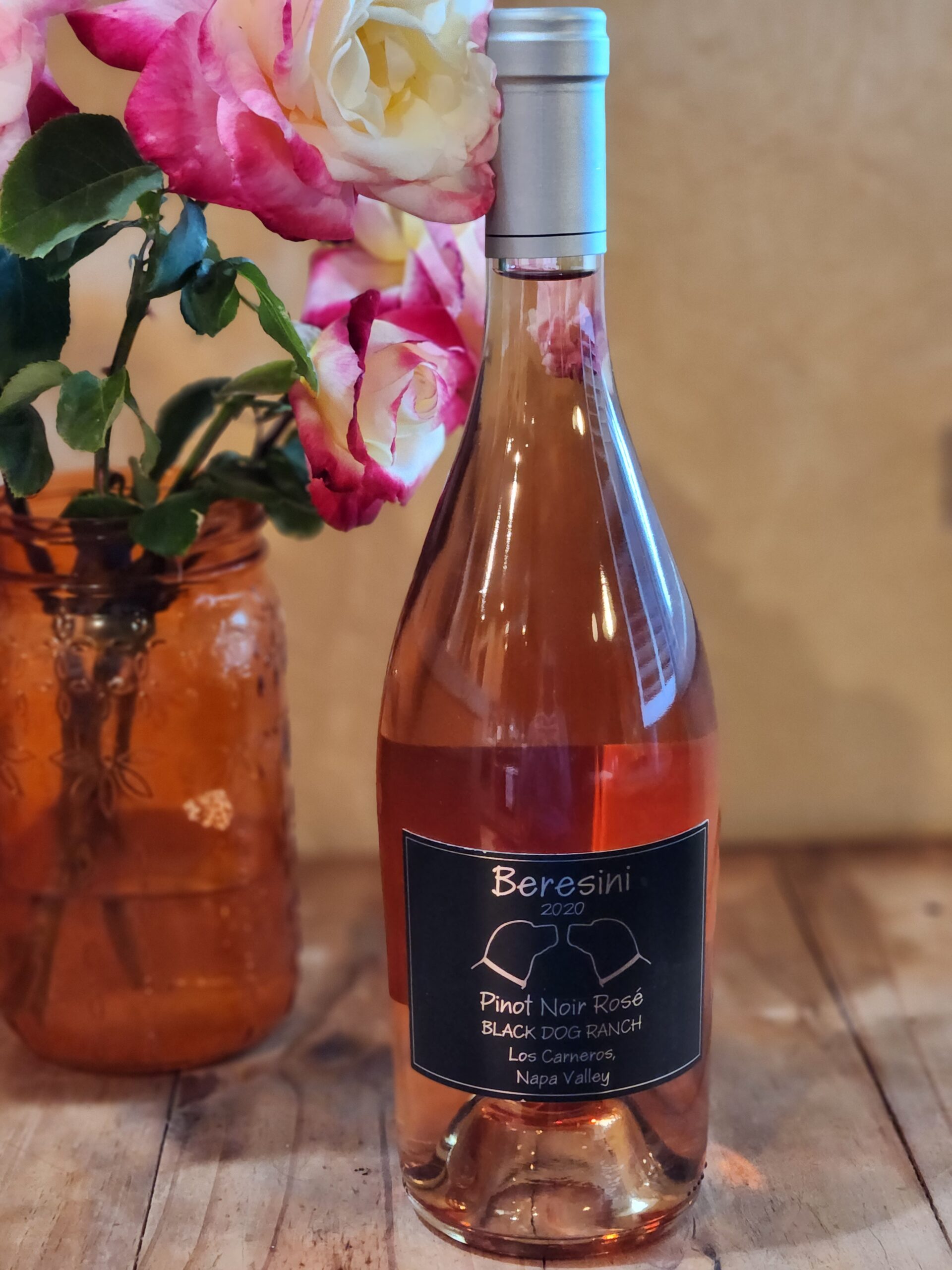 Bottle of 2020 Pinot Noir Rose on a picnic table next to flowers in a vase