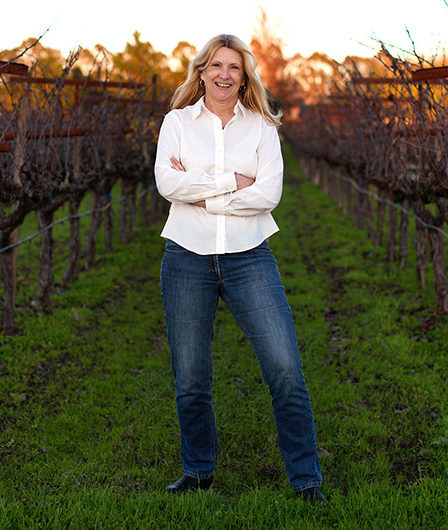 Co-Proprietor Debra Beresini standing in the vineyard at sunset